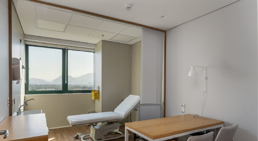 Sala de atendimento do Dr. Eduardo Tiburcio na Barra da Tijuca, com maca de exame e janela ampla