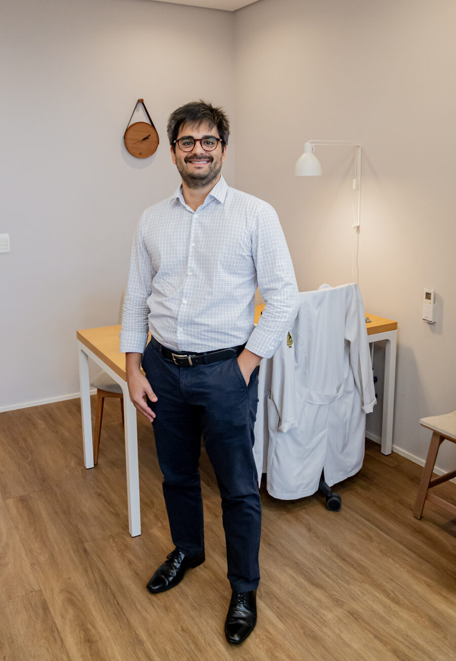 Dr. Eduardo Tiburcio, médico de família e comunidade, em pé no consultório da Barra da Tijuca